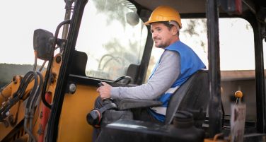 Operator maszyny budowlanej w kabinie koparki podczas pracy w kasku ochronnym