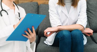 Pacjentka siedząca podczas konsultacji psychiatrycznej, a specjalista robi notatki na formularzu